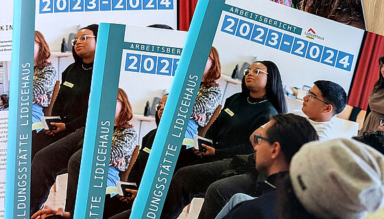 Foto von einem Stapel der gedruckten Arbeitsberichte des LidiceHauses. Auf dem Titelblatt sind mehrere Personen zu sehen, die einem Seminarraum sitzen. Folgender Text ist zu lesen: Arbeitsbericht 2023-2024, Jugendbildungsstätte LidiceHaus. Demokratie braucht politische Bildung. Außerdem ist eine Aufzählung unserer Schwerpunktthemen zu sehen: Partizipation, Demokratiebildung, Erinnerungspädagogik, (Historisch-)Politische Bildung, Migration, Antidiskriminierung und Empowerment, Antisemitismuskritische Bildung, Rassismuskritische Bildung, Themenfeld Rechtsextremismus, Internationale Jugendarbeit, Jugendinformation, Medienpädagogik